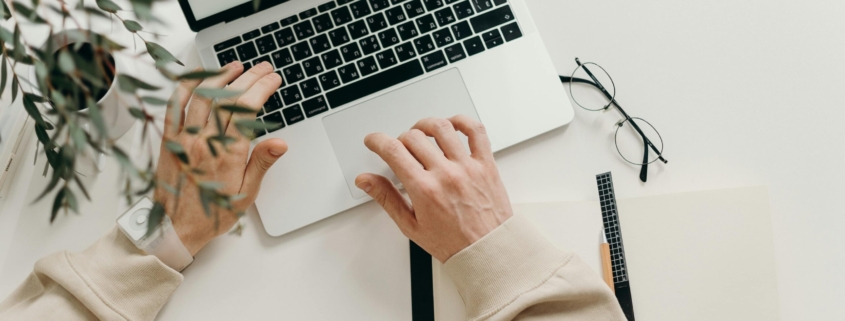 Free An overhead view of a person working on a laptop in a minimalist home office setting. Stock Photo