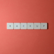 Free Close-up of keyboard keys spelling 'BACKUP' placed on a coral-colored surface. Stock Photo