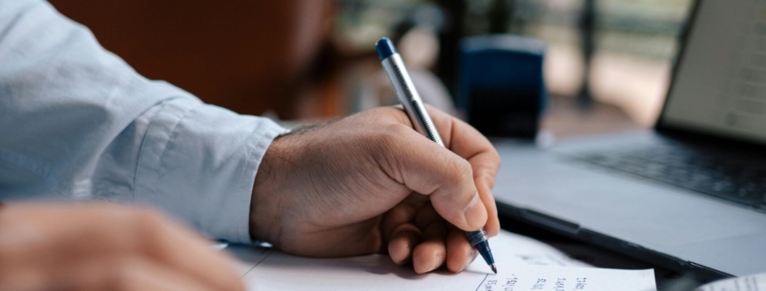 Free A person calculating finances with a calculator and pen on a desk indoors. Stock Photo