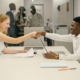 Free Business professionals completing a successful deal with a handshake in a modern office setting. Stock Photo